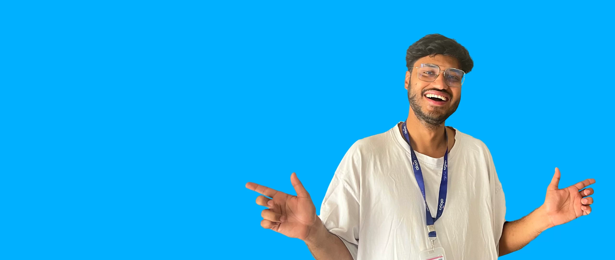 A man with glasses and a white shirt, smiling widely, poses against a vivid blue background