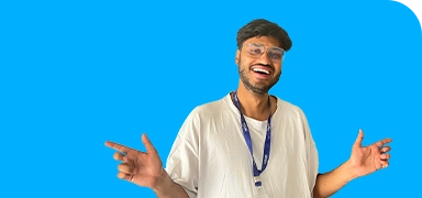 A man with glasses and a white shirt, smiling widely, poses against a vivid blue background