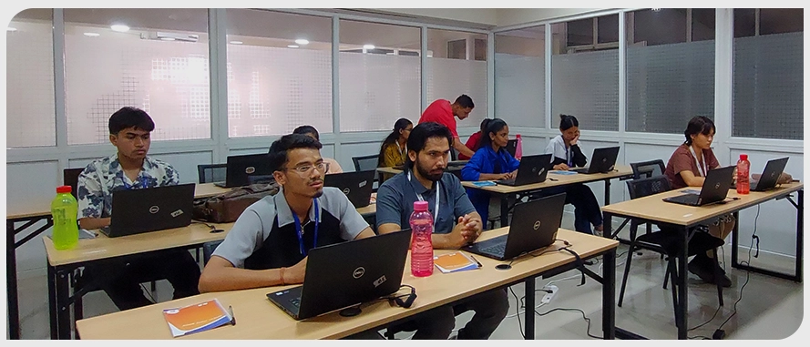 Individuals are seated at desks, each using a laptop.